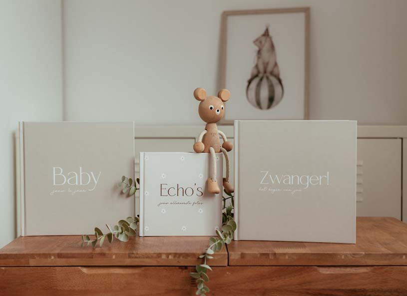 De boekjes Zwanger!, Echo's en Baby naast elkaar op een houten plank, met een houten beertje en een takje eucalyptus.